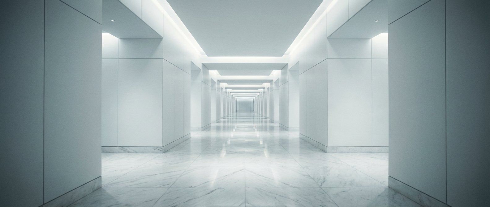 Corredor largo y moderno con paredes blancas, suelo de mármol brillante y luz ambiental empotrada en el techo.
